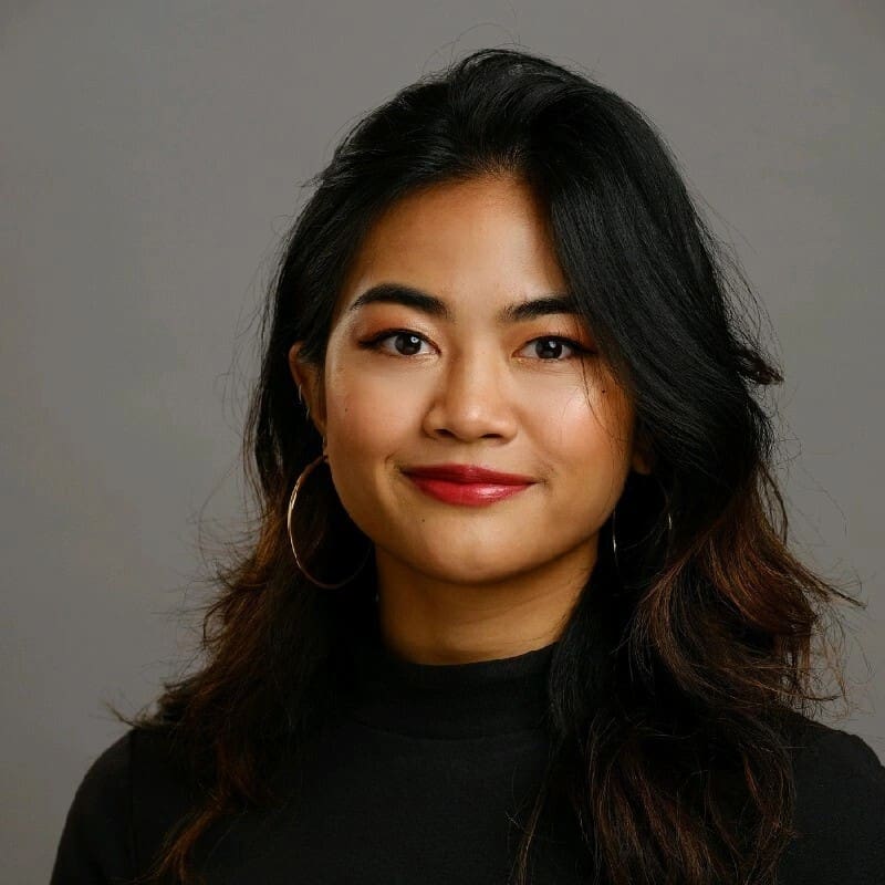 Smiling woman with long dark hair and red lipstick, wearing a black turtleneck. #nextgenmarketers